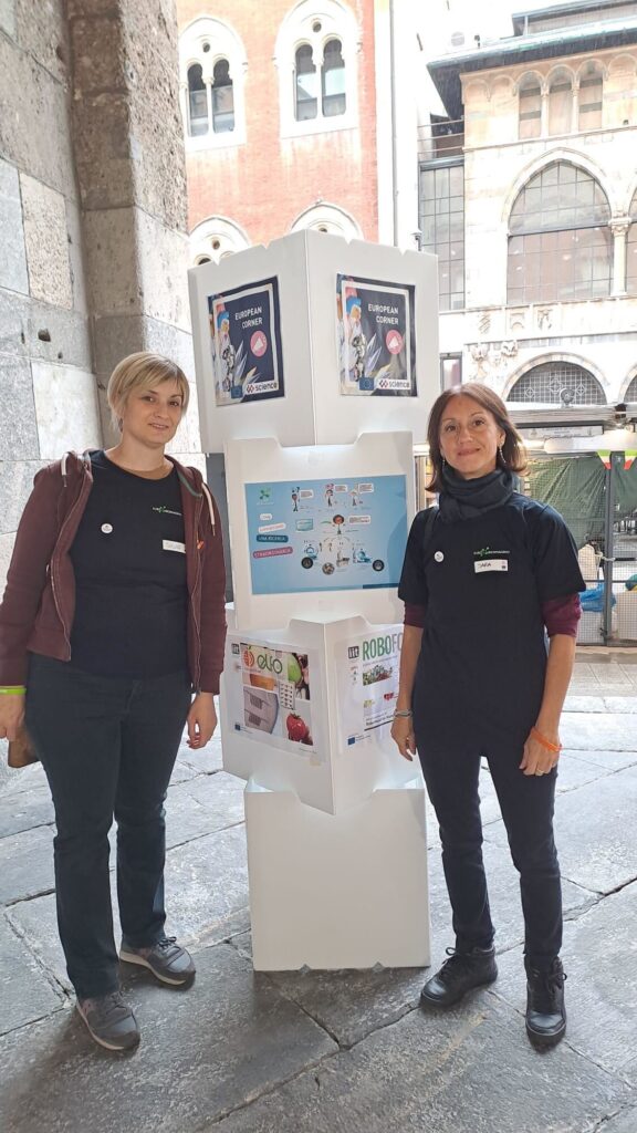 Two women in front of a poster at an outdoor science event.