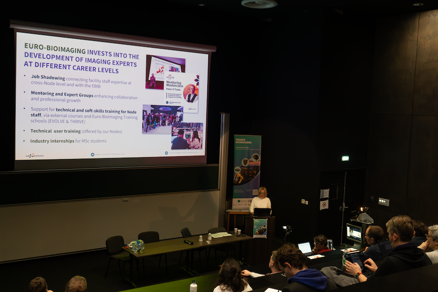 Claudia Pfander presenting in front of a large screen in an auditorium.