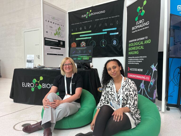 Photo of Claudia Pfander and Yara Reis in front of the Euro-Bioimaging booth