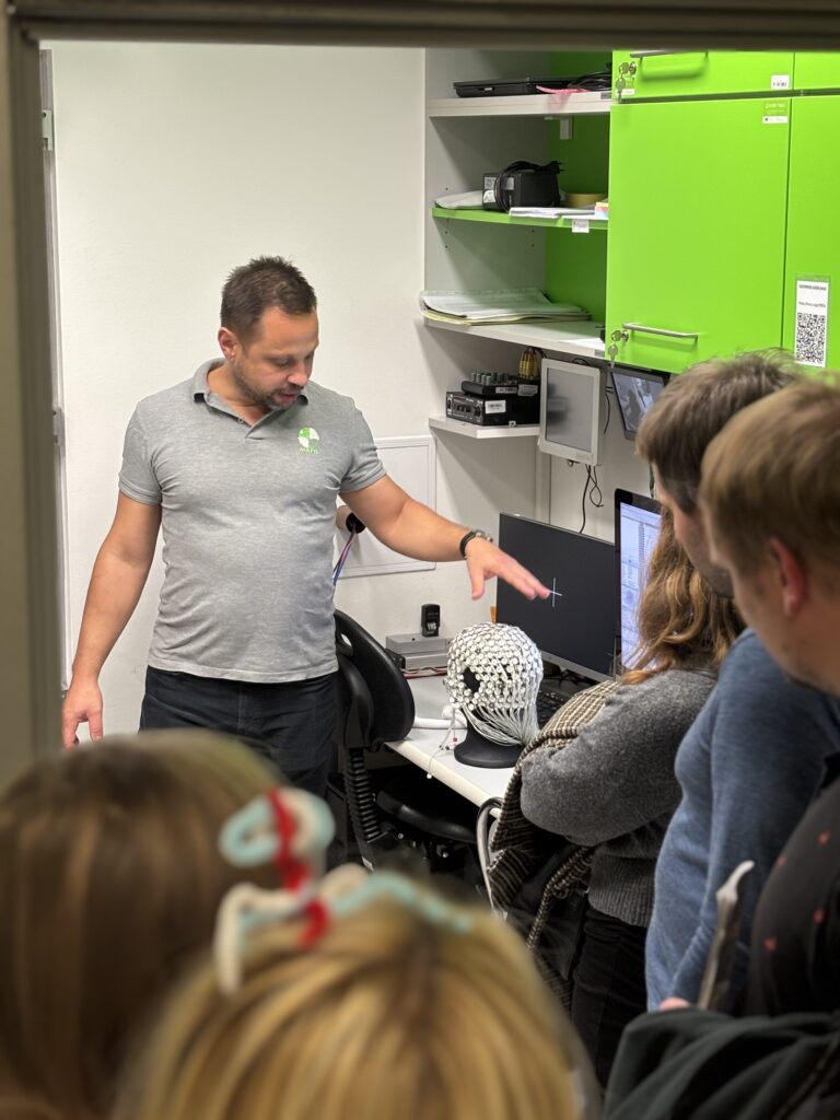 A man in a crowded room showing the HydroCel Geodesic Sensor Net.