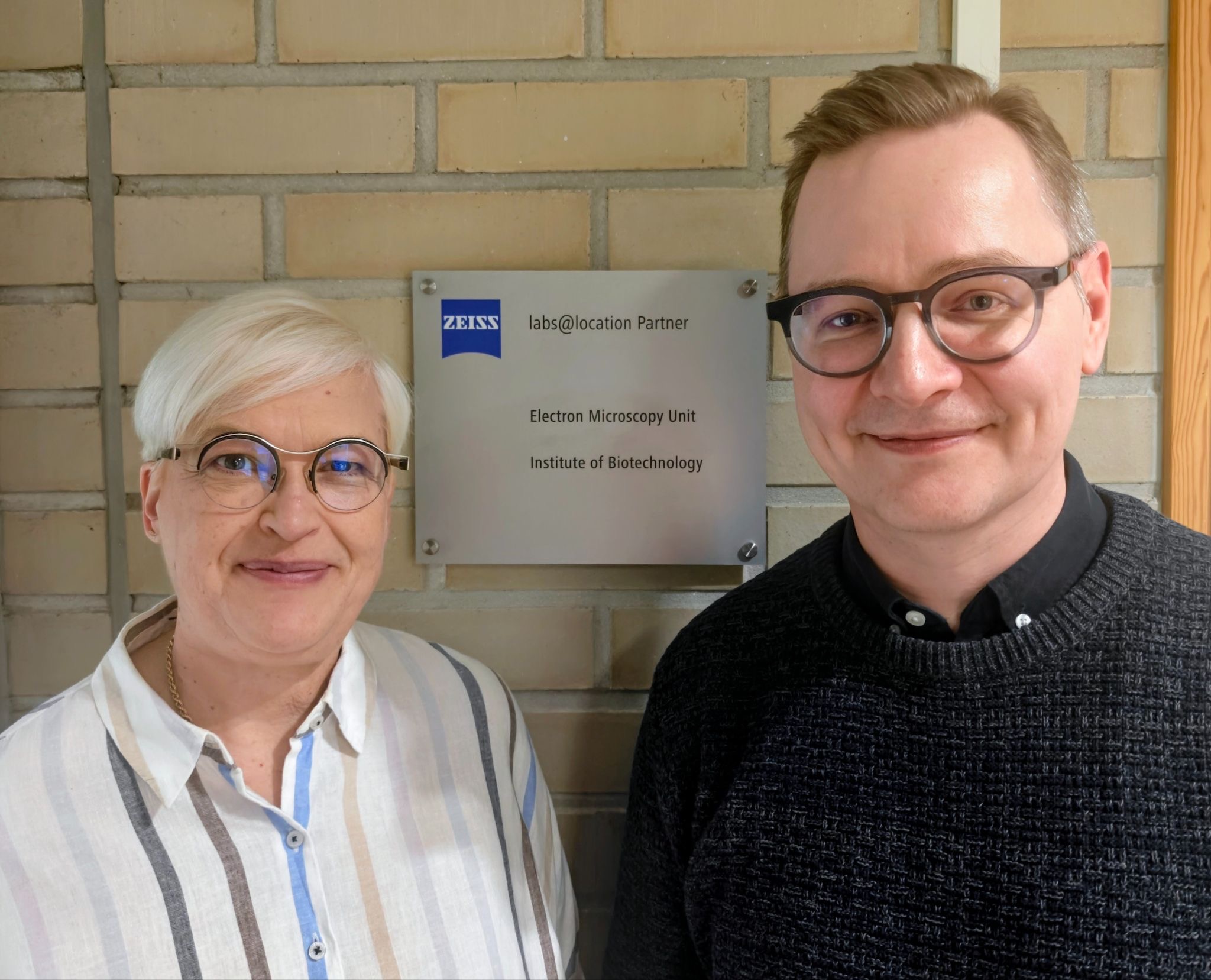 A woman and a man in front of the ZEISS labs@location plaque.