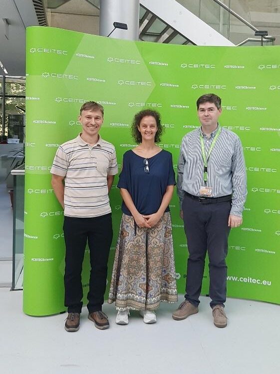 Three people in front of a CEITEC poster.